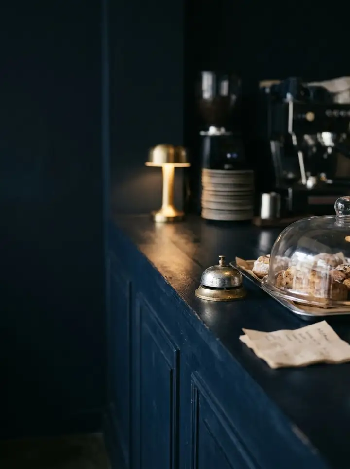 A small cafe counter with a brass bell and a warm lamp.